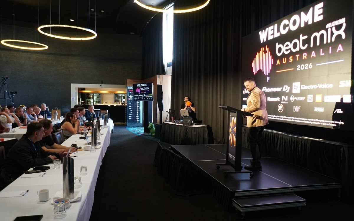 Presenter at a lectern in front of an LED wall at an industry conference